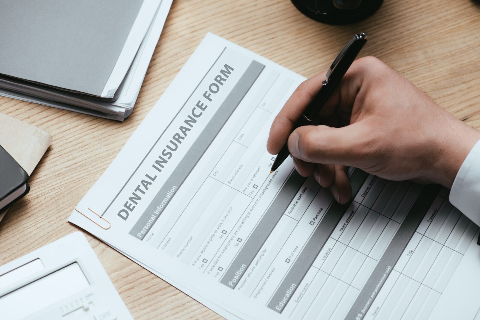 cropped-view-of-man-filling-in-dental-insurance-form-dentist-concept-1600x1068