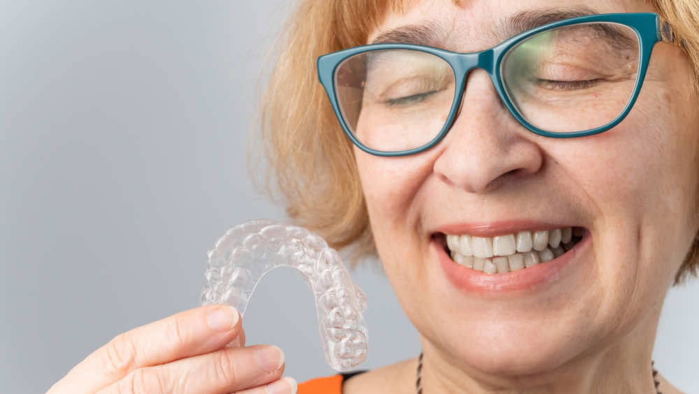 older-woman-holding-clear-aligners